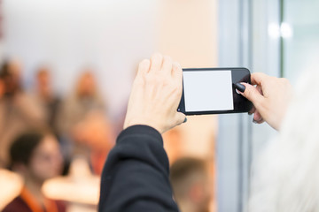 Fototapeta na wymiar Hands holding smartphone with empty screen en against blurred people background.