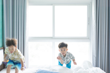 brothers are jumping and playing in the morning on the bed.