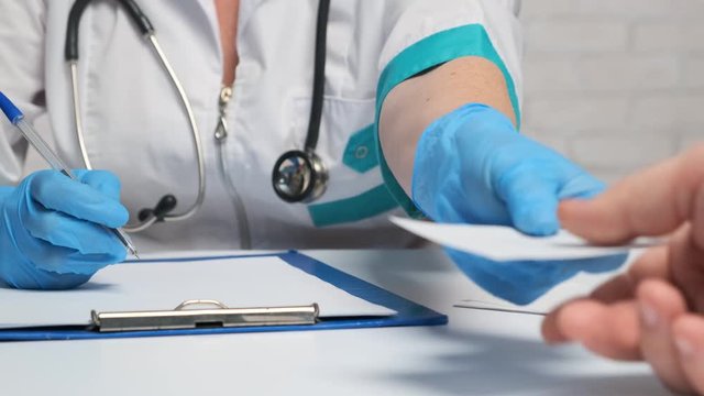 woman doctor pulls a note to a man at a clinic reception.