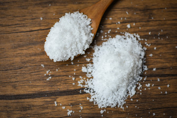 Fototapeta na wymiar Salt in wooden spoon and heap of white salt on wood background