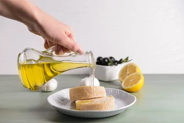  Woman pouring tasty olive oil from bottle onto fresh bread © Pixel-Shot