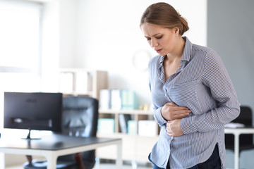 Young woman suffering from stomachache in office