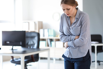Young woman suffering from stomachache in office