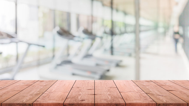 Empty wood table top on blurred with bokeh Exercise room,fitnees and gym interior banner background - can be used for display or montage your products
