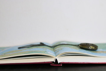 Primo piano di un atlante e orologio da taschino vintage, viaggi e geografia © Sara