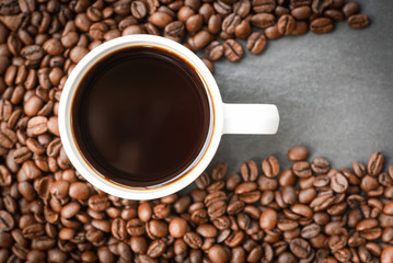 coffee cup on roasted coffee beans on the dark background top view