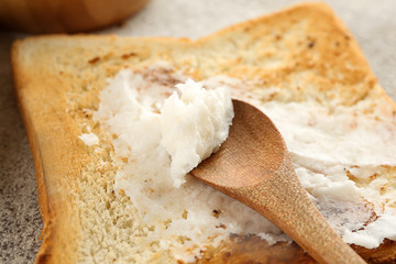 Tasty toasted bread with coconut oil and spoon, closeup