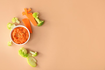 Bowl with healthy baby food on color background