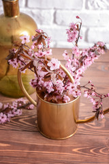 Watering can with beautiful blossoming branches on wooden table