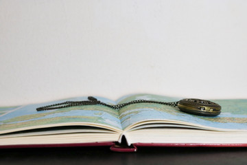 Primo piano di un atlante e orologio da taschino vintage, viaggi e geografia © Sara