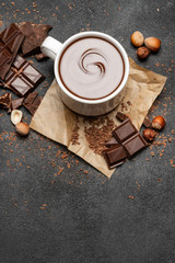 Cup of hot chocolate and pieces of chocolat on dark concrete background