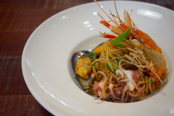 Spicy Seafood Spaghetti stir fried (Pad Cha) rolled in the fork on white dish of luxury restaurant