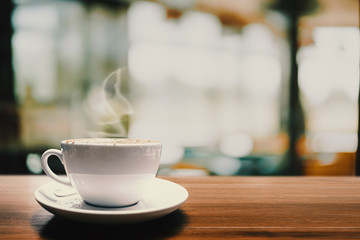 Hot coffee cup on wood table in cafe for background.