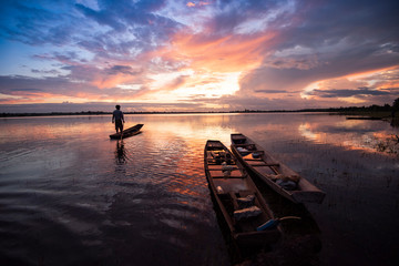 fisherman on fishing boat silhouette sunset or sunrise in the river lake beautiful sky background