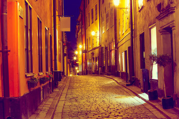 Fototapeta na wymiar The narrow cobblestone street with medieval houses of Gamla Stan historic old center of Stockholm in the evening twilight sunset. Toned image