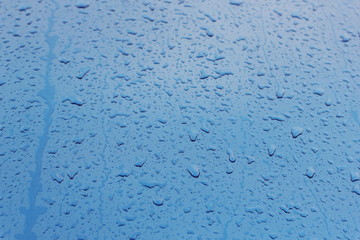 Water droplets on the reflective wet blue metal texture