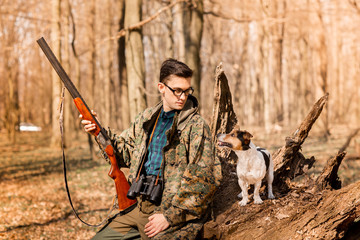Portrait of a yang hunter with a dog on the forest