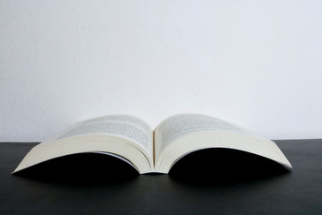 Libro di letteratura aperto appoggiato su un tavolo nero con lo sfondo bianco
