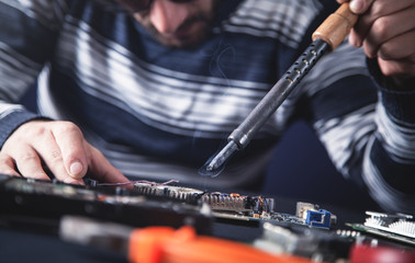 Computer hardware engineering. Engineer soldering computer motherboard