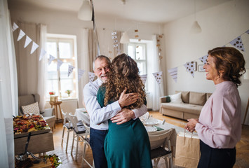 Young woman greeting parents or grandparents on a indoor birthday party.