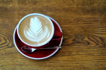a cup of late art hot coffee, top-view on the wood table 