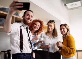 A group of young business people with smartphone at work, taking selfie.