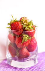 glass of red ripe strawberries on a light background