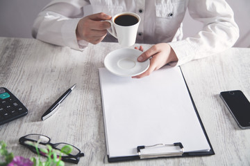 Business girl holding coffee cup in office desk.