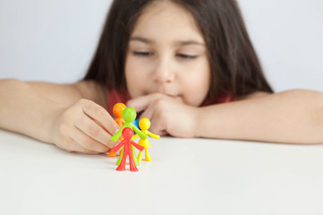 Obraz na płótnie Canvas Happy traditional family figurines. A small child plays with colored plastic figures. Mom, dad, brother, sister, siblings. Family symbol. Adoption. Full family. Face out of focus. 