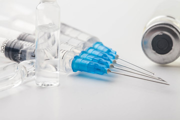 Subcutaneous syringe. Syringes with blue needles. Medical Injectors. Medical glass injection bottle. Ampoules with injections.
