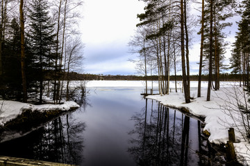 Natural landscape - forest, lake,river are under snow in spring in March