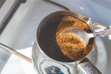 Barista preparing hot tasty drink from copper turk, boils water for coffee on small fire in cezve. Coffee turk made of organic copper, cezve to kitchen. Copper turk for real gourmet coffee at cezve