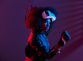 Stylish curly dark haired girl dressed in black leather jacket and gloves is wearing the virtual...