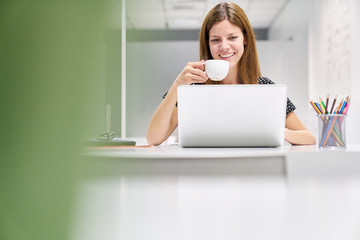 Business Frau am Laptop  trinkt eine Tasse Kaffee