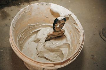 Man is mixing spackling paste putty in the bucket. Grind of wall. Maintenance repair works...