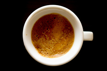 Primo piano di una tazzina di caffe vista dall’alto con lo sfondo nero, bevande e cucina