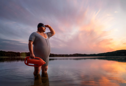Funny retro lifeguard standing in the water and looking away with copy space