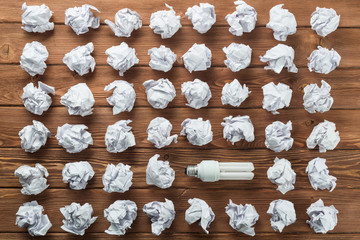Ideological concept with wastepaper light bulb on wooden table