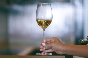 Closeup image of a woman's hand holding a wine glass with blurred background
