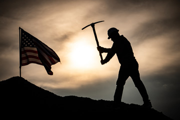 Concept Labor Day: Labor man standing holding a pickaxe with the United States flag