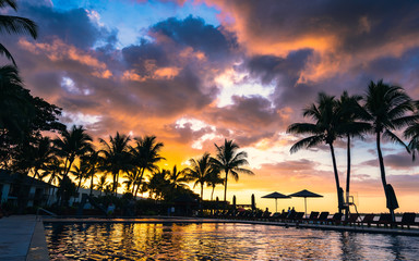 Dramatic sunset over a tropical resort pool