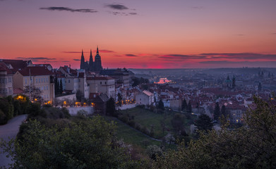 Obraz premium A beautiful spring view of Prague at sunrise from Petrin hill. Prague Castle and St. Vitus Cathedral on the left and a golden rising sun in the background