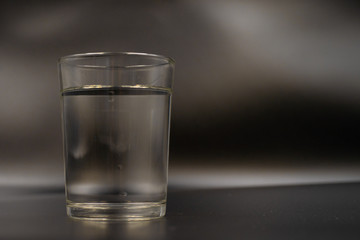 Just a glass of water on a dark wooden table. Mineral water in a glass on a black background. A...