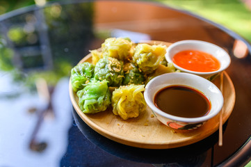 Yellow and green dumpling dim sum stuffed with pork and shrimp with sauces