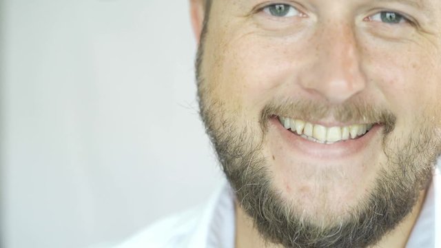 Handsome Caucasian man with a beard smiling on a white background, portrait of a man half face.