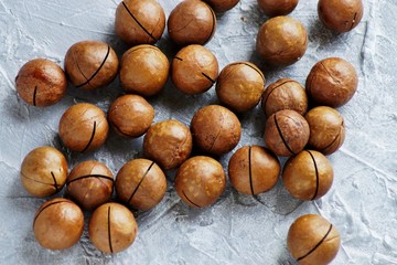Not peeled , shelled macadamia nuts on a gray concrete background, snack on a Keto diet