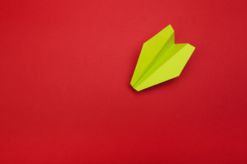 Flat lay of colour paper plane on red background with text space.