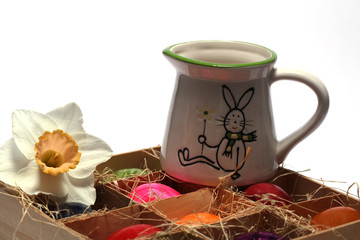 Osterschmuck mit bunt bemalten Eiern und einer Kanne mit Ostermotiv