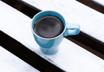 Fragrant coffee in a beautiful cup. Cup outdoors on a wooden table.