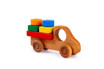 Photo of a wooden car truck loaded with small colorful wooden geometric figures: a circle, a triangle, a rectangle, a square made of beech on a white isolated background